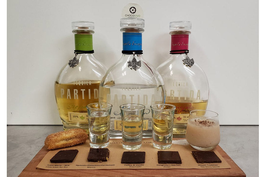 Bottles of tequila with a selection of drinks on a board with Dark Chocolate pieces